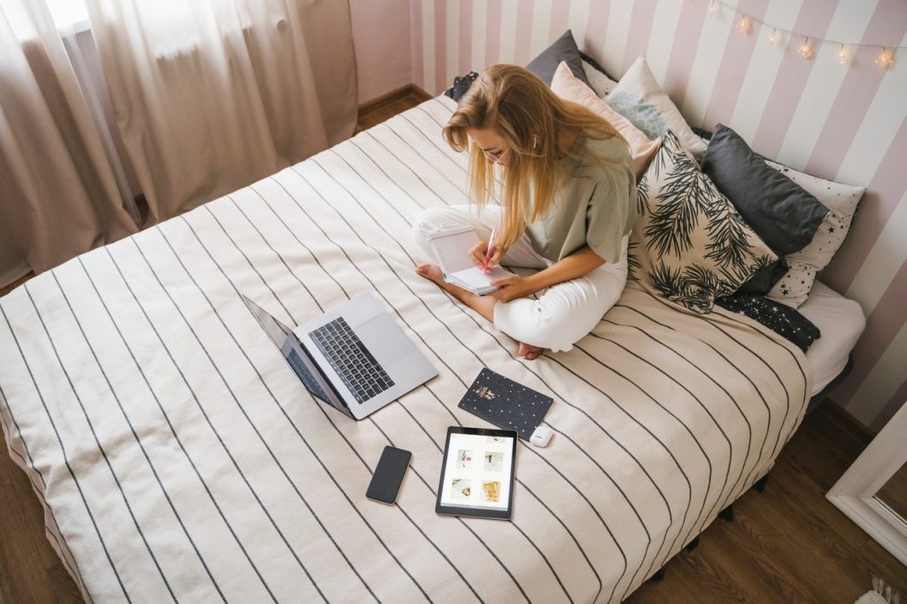 woman sitting on her bed taking notes